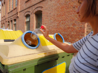 woman throwing plastic bottle Recycling bin stand on european street. Waste separation rubbish before drop to garbage bin to save world, environment care. Pollution trash recycling management concept