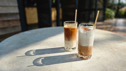 A glasses of milk coffee on cement table outdoor with sunlight. Summer drink