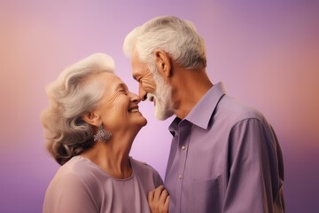 
Elderly loving couple, both in their late 70s, Hispanic, enjoying a moment of closeness with their foreheads touching against a gentle lavender pastel background with copy space