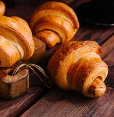 Appetizing croissants on wooden table close-up