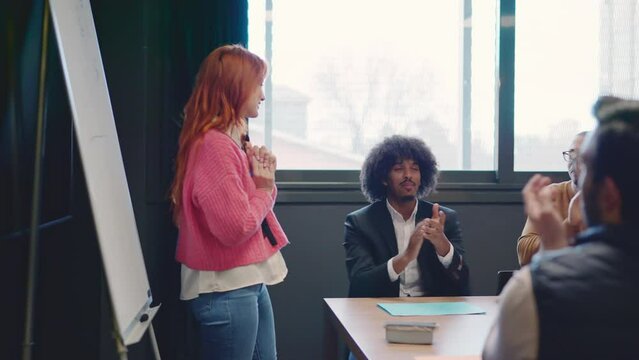 Coworkers applauding and congratulate a woman after a speech