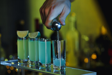 Bartender pouring alcohol drink into shot glass on blurred background, closeup. Space for text