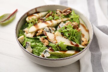 Delicious pear salad with sauce in bowl on light table, closeup