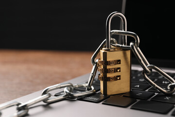 Cyber security. Laptop with padlock and chain on table, closeup