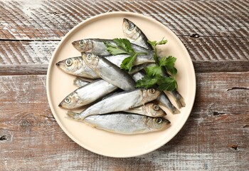 Fresh raw sprats and parsley on wooden table, top view