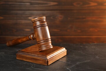 Wooden gavel and sound block on dark textured table, closeup. Space for text