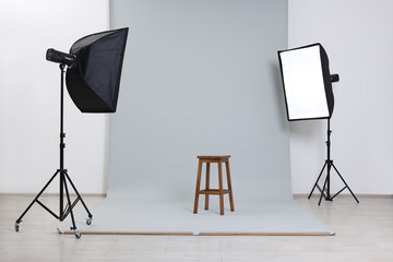 Empty stool surrounded by professional lighting equipment in photo studio