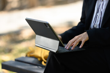 Young businesswoman with digital tablet sitting on park bench in the park on a sunny day