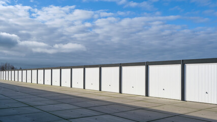 A row of garages or storage units on an industrial site under a sky with large dark clouds