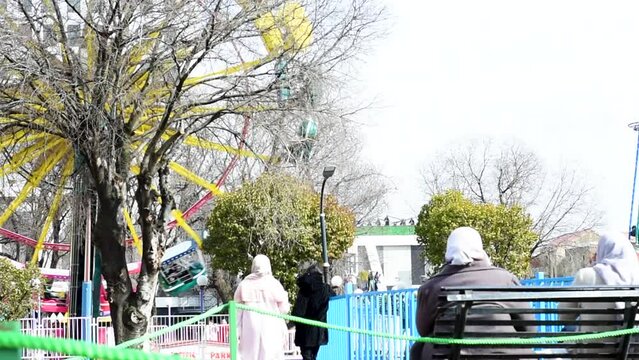 Back view of women sitting on the bench in the amusement park in Setif City. Algeria.