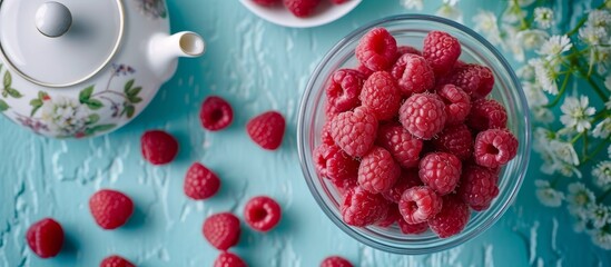 Healthy breakfast concept with fresh raspberries in a bowl and a cup of tea on wooden table