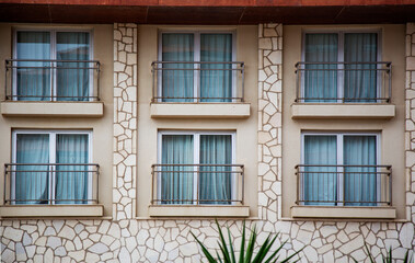 Details of the stone wall facade of a two-story building with windows and balconies