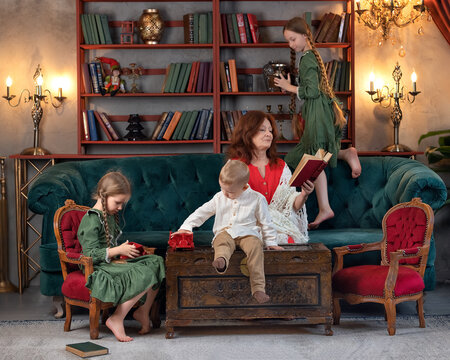 Happy grandma and grandchildren reading book together and having fun at home