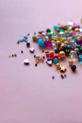 Various colorful beads on bright pink background. Selective focus.