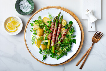 Spring salad with grilled green asparagus wrapped with bacon, boiled new baby potatoes, fresh corn...