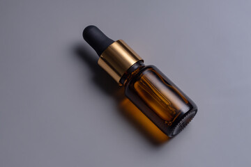 Amber glass cosmetic dropper bottle with blank label on grey background. Trendy beauty product design, branding. Mockup cosmetics