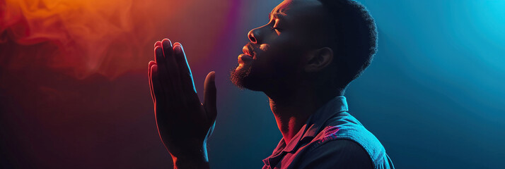 African American Man prays to god on black studio background - obrazy, fototapety, plakaty