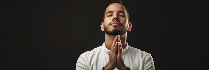 Naklejka premium Latin American man prays to god on black studio background