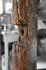 Rotting.  Old wooden post with cut-out and holes against a black and white background in an alley in Bangkok.