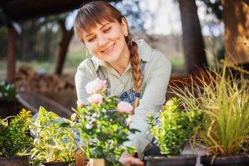 Young adult happy European woman on the terrace of a country house with a pot of spring flowers in her hands. Gardening as a hobby and spring lifestyle - 746384851