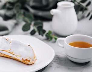 eclair with meringue and cup of tea