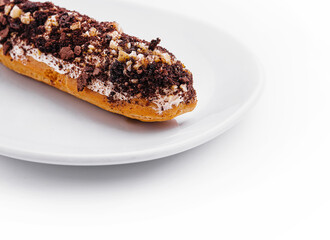eclair with chocolate and nuts on a white plate