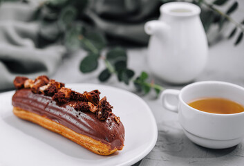 Eclair with Chocolate Cream and Hazelnuts and tea