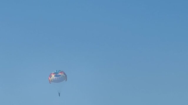 Parasailing above the sea, colourful parachute soaring in clear blue sky