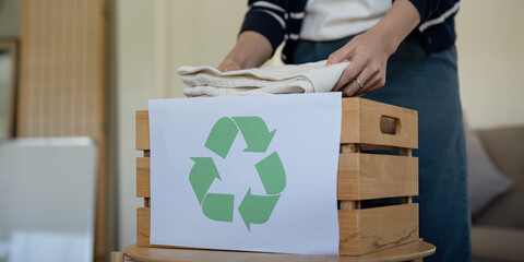 Woman pack box with used clothes for reuse. Reusing, recycling material and reducing waste in...