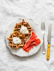 Zucchini potatoes waffles with lightly salted salmon and fresh cream on a light background, top view