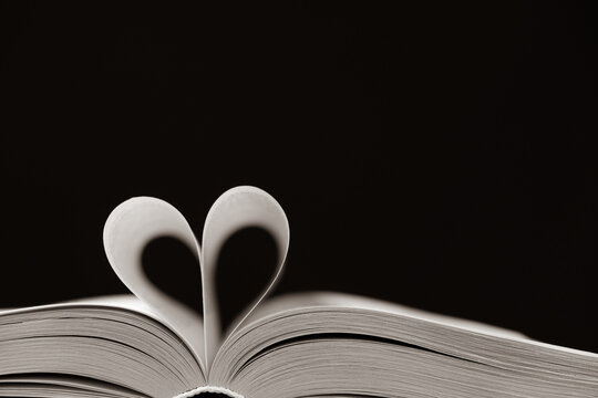 The pages of the book are folded in the shape of a heart on a black background, place for text