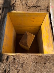Agujero con una primera piedra para una inauguración de un edificio.  Agujero en el suelo de una obra, para ceremonia colocando prisma de hormigón como primera piedra y una capsula del tiempo.
