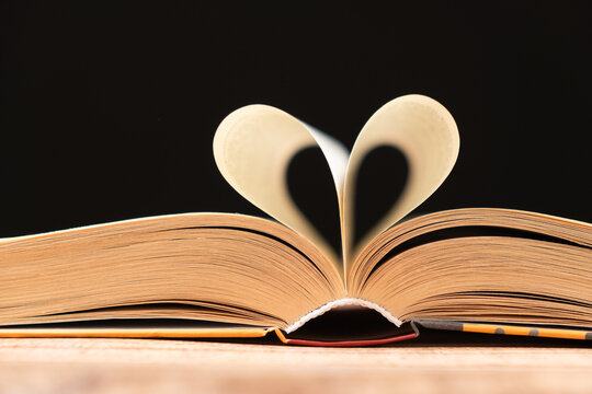 The pages of the book are folded in the shape of a heart on a black background, place for text