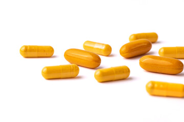 Yellow Capsule Pills Scattered on a White Background