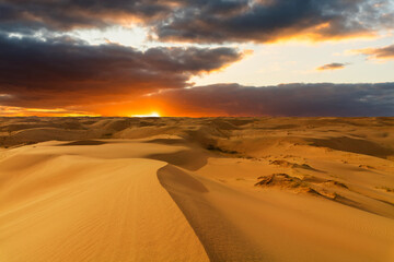 Fototapeta na wymiar Dramatic sunset over the sand dunes in the desert. Gobi desert