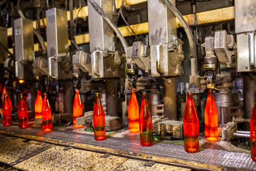 Glass factory, production of glass containers. Molten glass is blown into molds. Robotics in industry. Modern technologies, robotic machines produce products. Technological work at the plant.