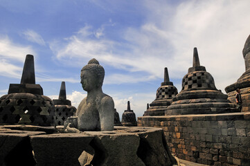 Stone Buddha sculpture enclosed in bell shaped stupa on Borobudur Temple in Central, Java,...