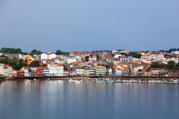 Fototapeta na wymiar The coast of the Spanish city of Feroll with colorful houses near the water and yachts at the piers.