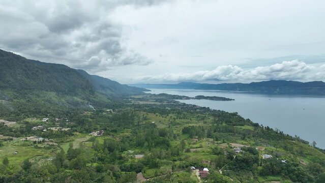 Verdant Samosir Island amidst the expansive Lake Toba, under a dramatic cloudy sky