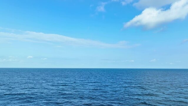 Aerial vista reveals the boundless expanse of azure sea, adorned by majestic waves, beneath a canvas of blue skies and fluffy clouds. Sea stock footage. Nature loop video background. 4K.
