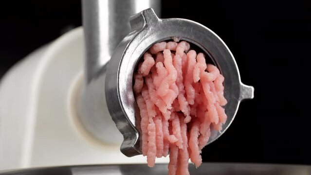processing pork meat in minced meat on a meat grinder, closeup