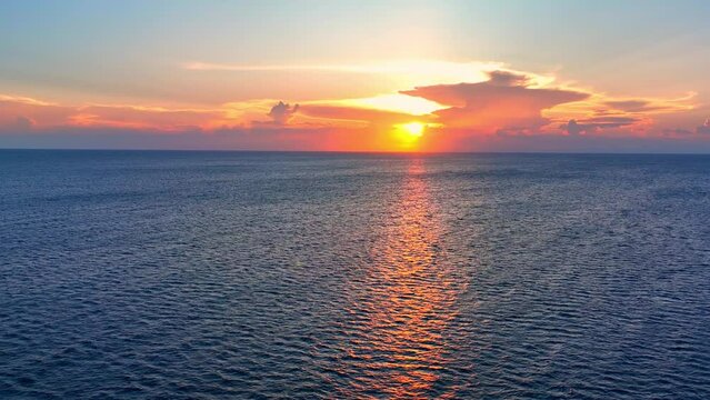 As the sun dips below the horizon, the sea mirrors its fiery hues, casting a spellbinding scene of summer's farewell. Flying from drone. Sea stock footage. Ocean background. 4K UHD.
