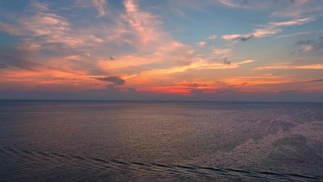 Capture the boundless beauty of the sea at sunset from a mesmerizing drone perspective. Golden hues paint the endless horizon. Aerial drone. High-quality video. Tropical sea background. 4K UHD.
