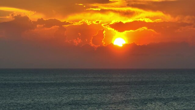 Capture the vast expanse of the endless sea under a golden sunset with a majestic sun, seen from above through drone aerial view. Bird's eye view. Stock footage. Tropical sea background. 4K.

