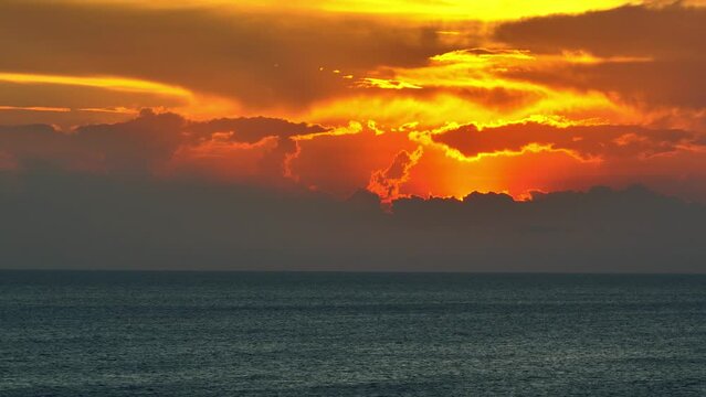 Amidst an epic sunset, the sea merges seamlessly with the sky, hues of yellow, orange, and pink merging in a breathtaking summer seascape. Aerial drone. Nature stock footage. Tropical sea background.
