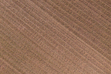Top-down perspective reveals the artistry of a brown plowed field, textured furrows creating a...
