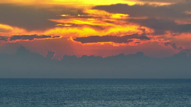 With the drone's lens, immerse yourself in a surreal sunset scene over the boundless sea, where the sky ignites in a spectrum of yellow, orange, red, and pink tones. Stock footage. Ocean background.
