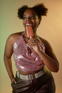 Happy woman eating orange ice cream against gradient background
