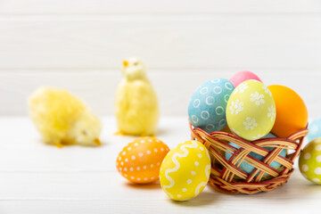 Easter basket filled with colorful eggs and a bouquet of tulips on a textured wooden table. Easter celebration concept. Colorful easter handmade decorated Easter eggs. Place for text. Copy space