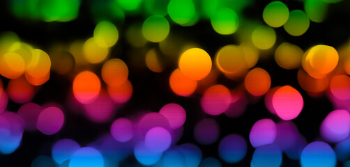 Soft defocused bokeh lights banner in multicolor on a dark background